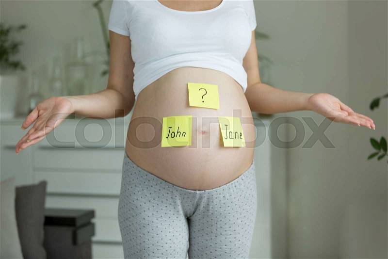Concept of choosing baby\'s name. Pregnant woman with names on belly, stock photo