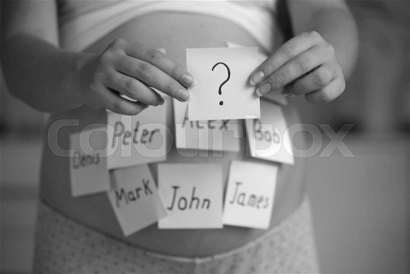 Black and white photo of pregnant woman choosing name for baby, stock photo