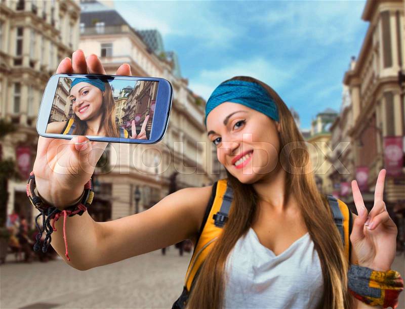 Happy traveler woman is taking selfie in a European street, stock photo