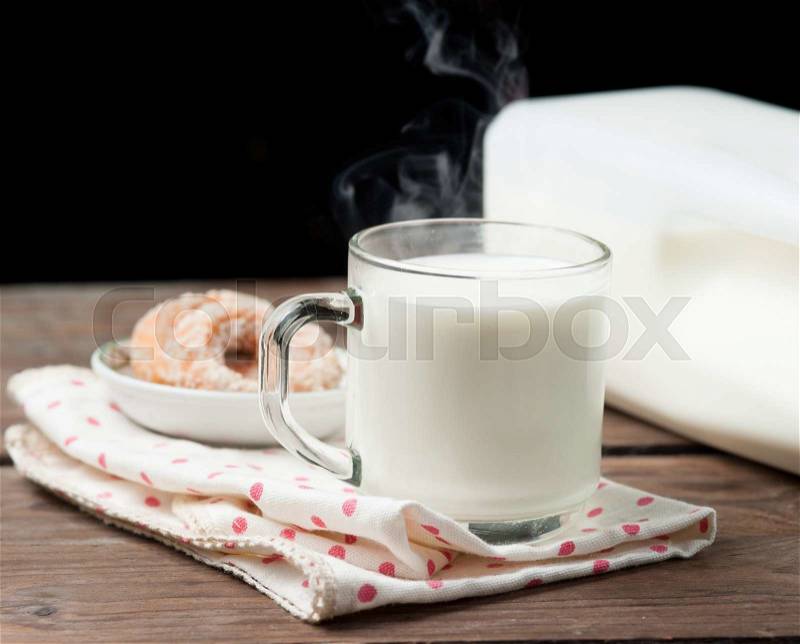 Hot milk in a glass with doughnut on wood, stock photo