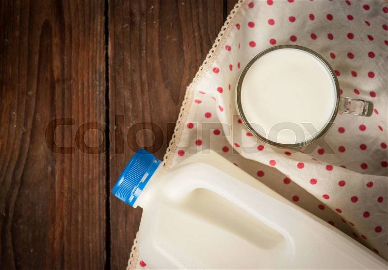 Gallon milk container and a glass of milk on wood, stock photo