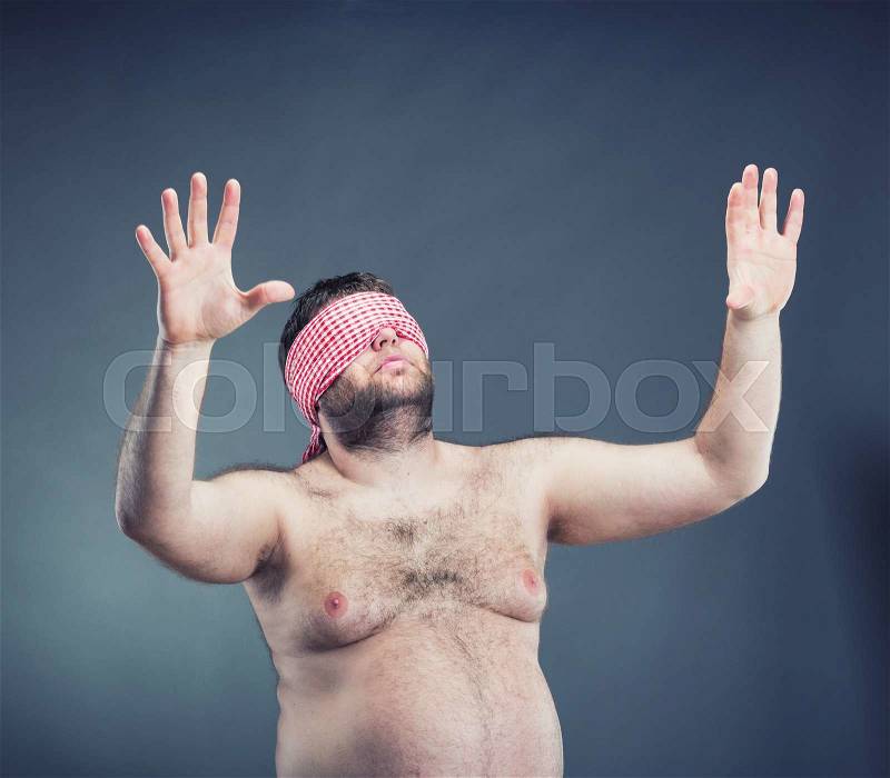 Portrait of the young fat man blindfold , isolated on gray, stock photo