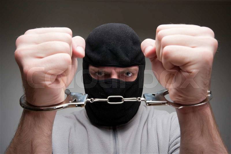 Close-up of angry criminal locked in handcuffs, stock photo
