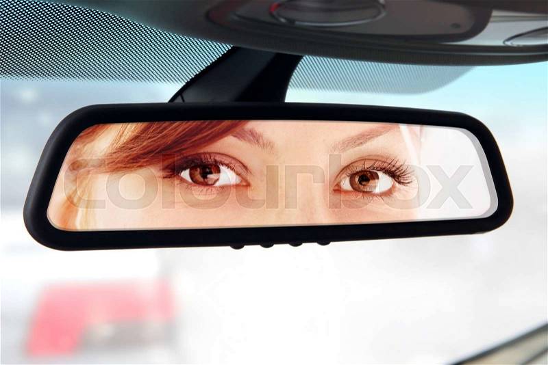 Woman sits on driver\'s seat and Looks in the rear-view mirror, stock photo