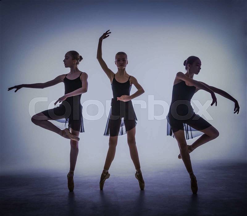 The silhouettes of young ballet dancers posing on a gray background, stock photo