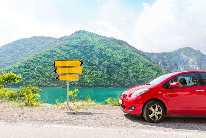 Red car in mountains and road pointer, stock photo