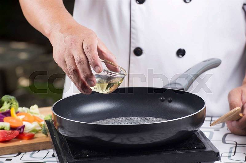 Chef pouring vegetable oil to the pan / Stir fried vegetable concept, stock photo