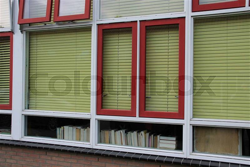 The old school with green shut blinds and a lot of books in the window is closed because collapse danger in the residential area in the village, stock photo