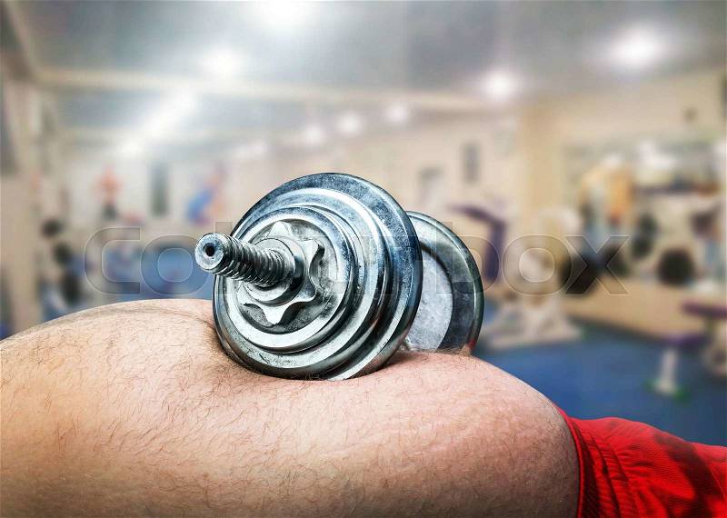 Dumbbell lying on fat male belly in the gym, stock photo