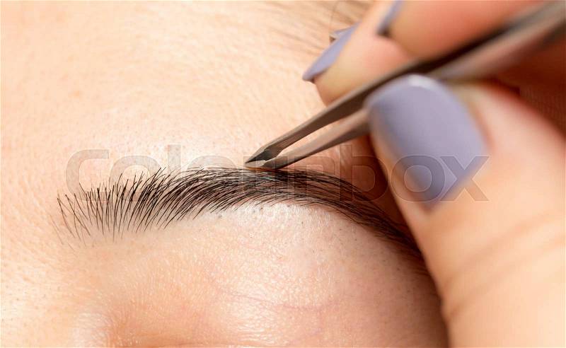 Grooming the eyebrows in a beauty salon, stock photo