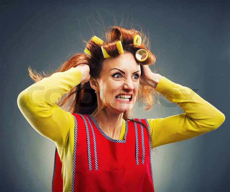 Crazy housewife with curlers isolated on gray, stock photo