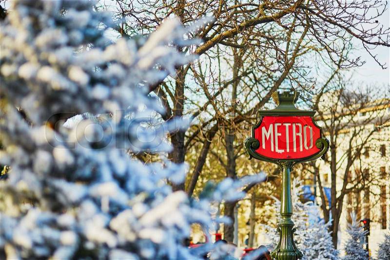 Parisian metro sign with trees covered with snow, stock photo