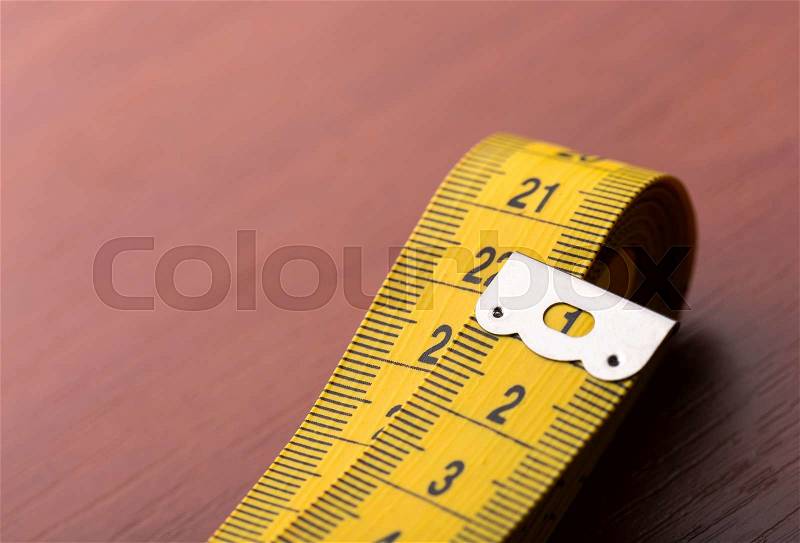 Closeup of measurement tape on the wooden table, stock photo