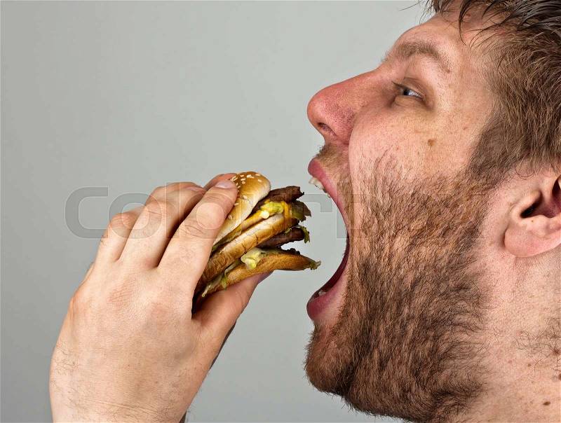 Close-up of bearded man eating juicy hamburger, stock photo