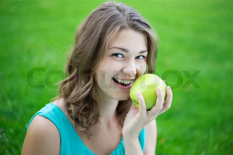 Happy beautiful woman with green apple in summer park, stock photo
