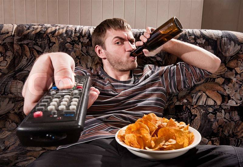 Man with beer and chips watching TV at home, stock photo
