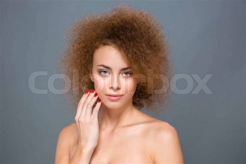 Portrait of sensual seductive natural young curly woman with red nails on gray background, stock photo