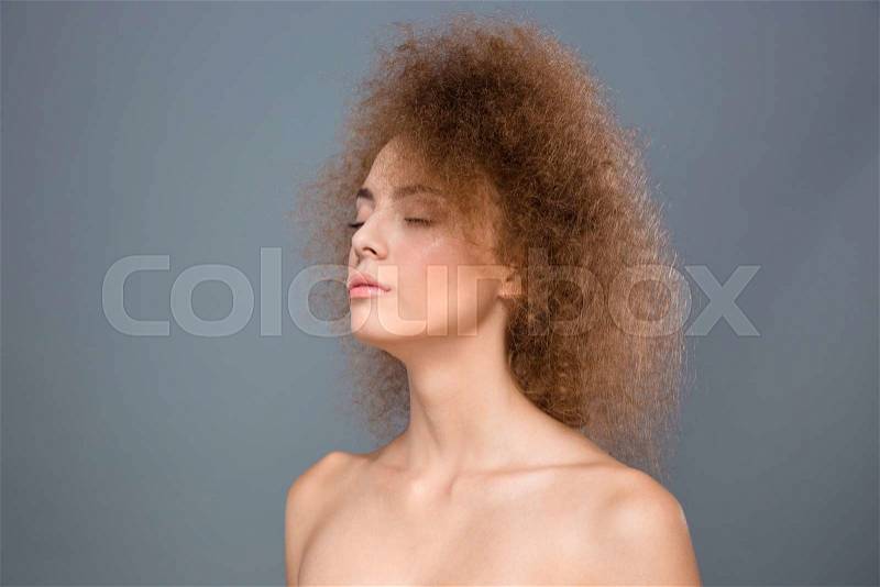 Closeup of young sensitive sensual natural female with curly hair on gray background, stock photo