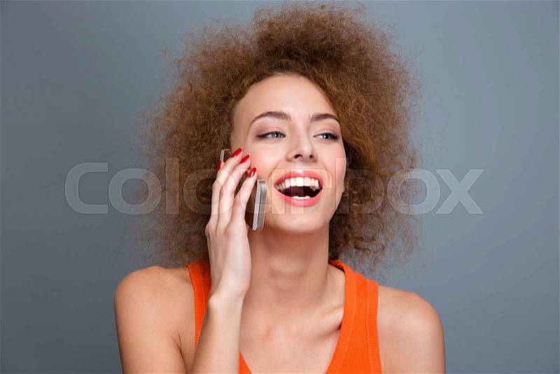 Happy delightful beautiful flirty curly woman talking on mobile phone and laughing, stock photo