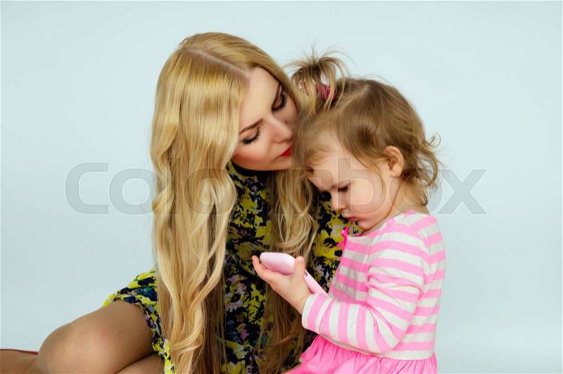 Young mother kissing daughter, stock photo