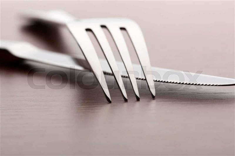 Closeup of fork and knife on wooden background, stock photo