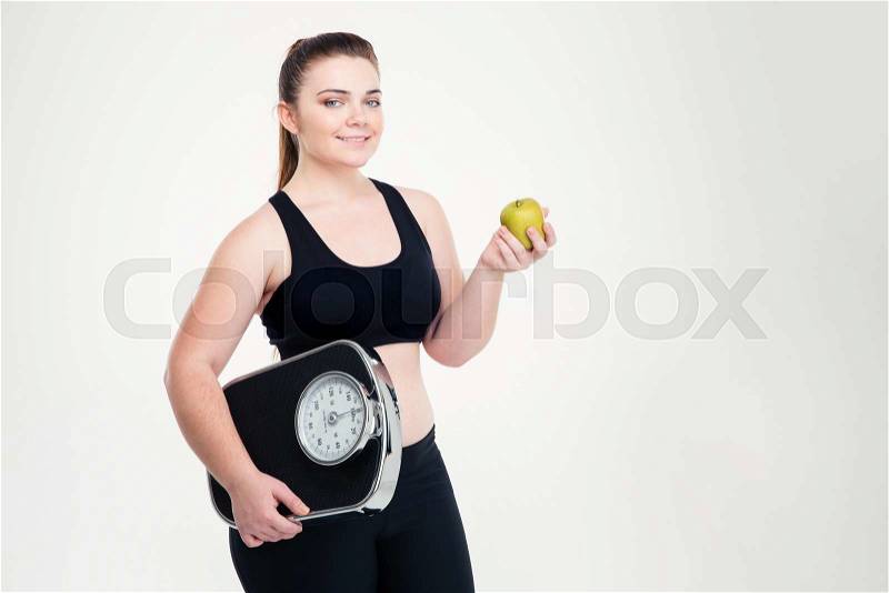 Portrait of a smiling fat woman holding weighing machine and apple isolated on a white background, stock photo