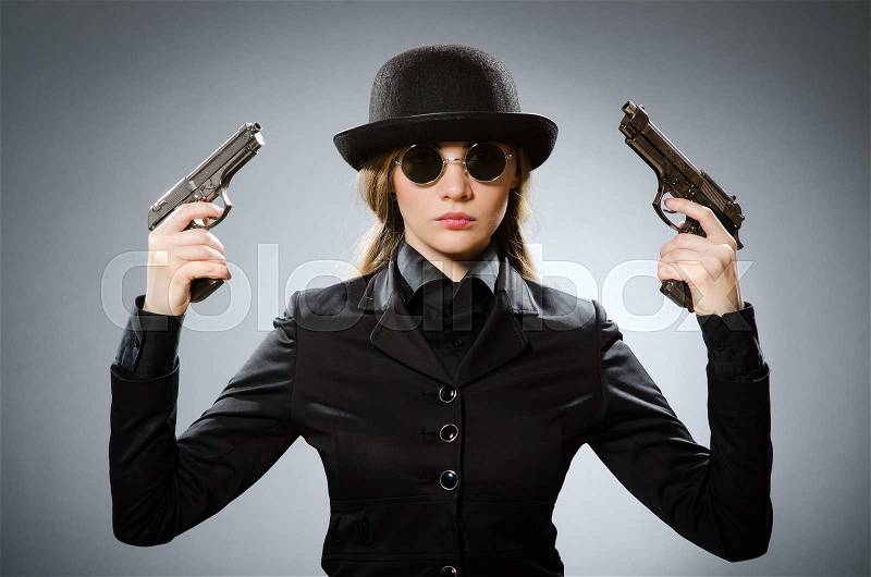 The female spy with weapon against gray, stock photo