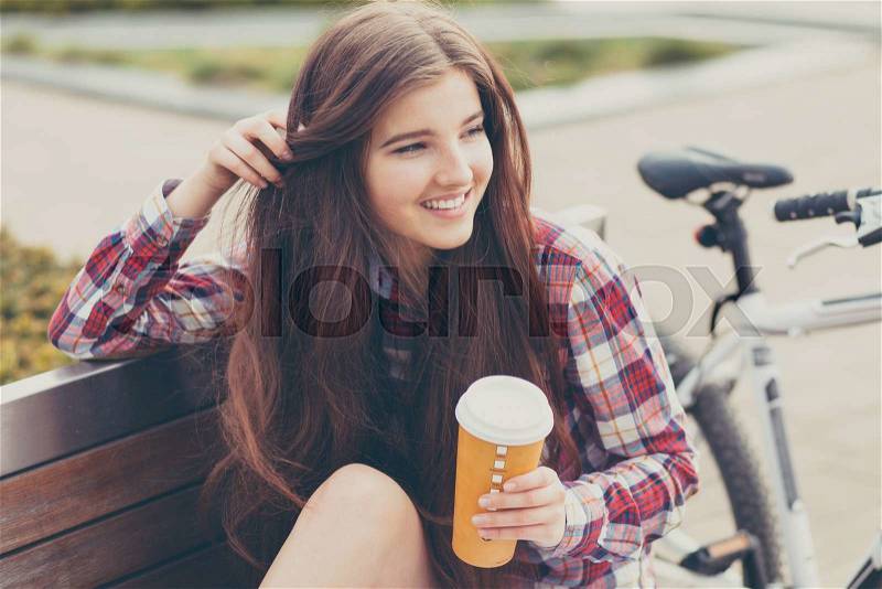 Young woman drinking coffee on a bicycle trip, stock photo