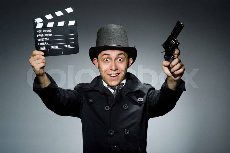 The young man with weapon and clapboard against gray, stock photo