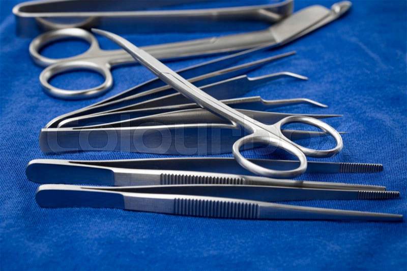 Detail of surgical instruments and tools on a tray covered with blue cloth, stock photo