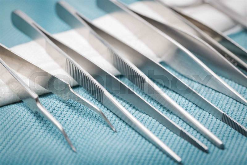 Detail of surgical instruments and tools on a tray covered with green cloth, stock photo