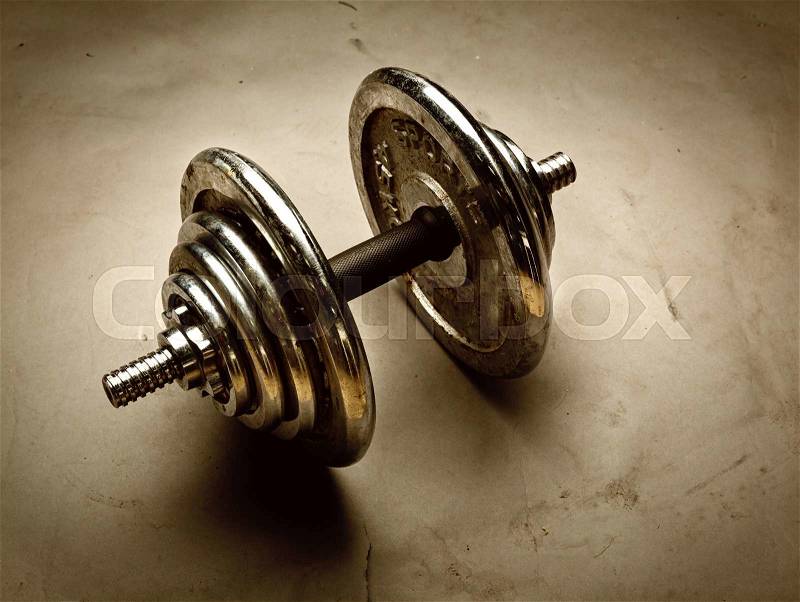 Old steel dumbbell weight on dark background. Toned, stock photo