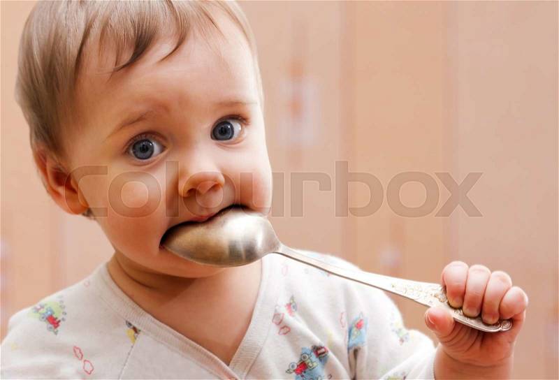 Portrait of baby girl holding spoon in mouth, stock photo