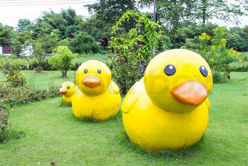 Yellow ducks decoration sculpture on green grass, stock photo