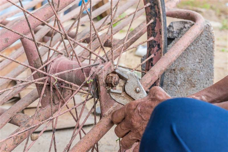 Close-up Of person hands repairs wheel bicycle with pliers, stock photo