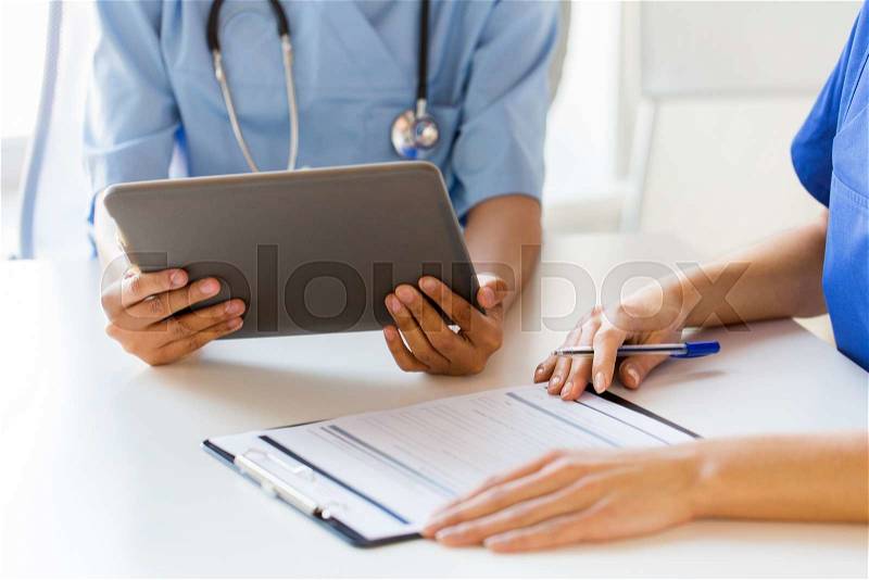 Hospital, profession, people and medicine concept - close up of doctors with tablet pc computer and clipboard meeting at medical office, stock photo