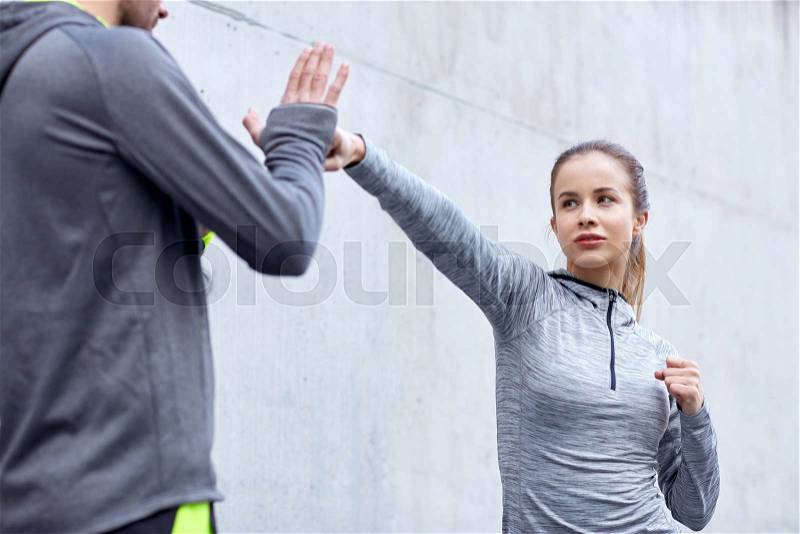 Fitness, sport, martial arts, self-defense and people concept - woman with personal trainer working out strike outdoors, stock photo