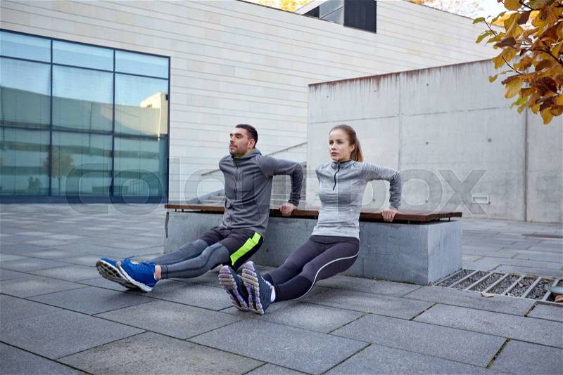 Fitness, sport, training, people and lifestyle concept - couple doing triceps dip exercise on bench outdoors, stock photo