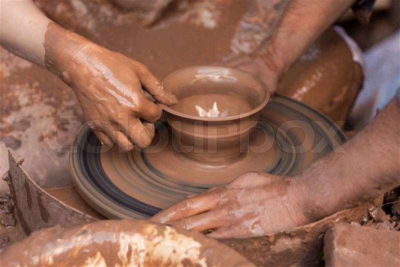 Potter teaches to sculpt in clay pot on a turning pottery wheel, stock photo