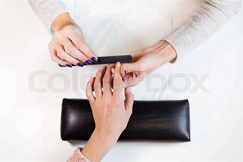 Top view manicure master nail file works on the pointing finger.Process of polishing fingers on towel in beauty salon, stock photo