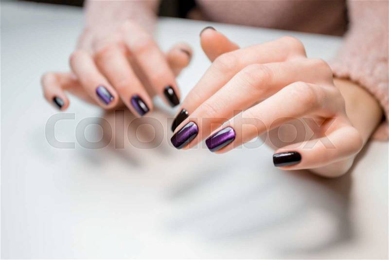Finished shellac manicure client girl in nail beauty salon. Hands lie on white table and show the beautiful manicure, stock photo