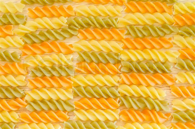Color penne pasta. Tomato, spinach and wheat pastas texture as background, stock photo