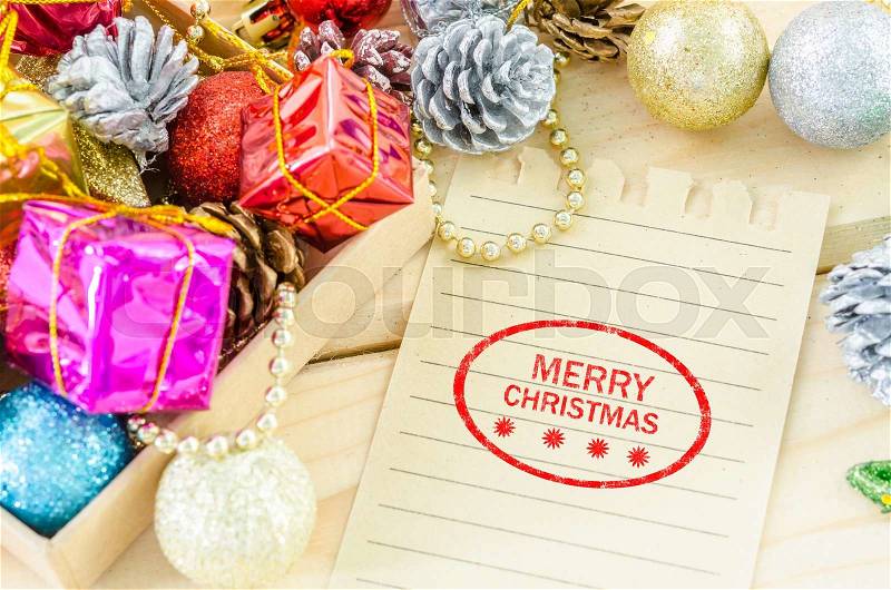 Banner and logo saying merry christmas on brown paper with christmas decorations on wood background, stock photo