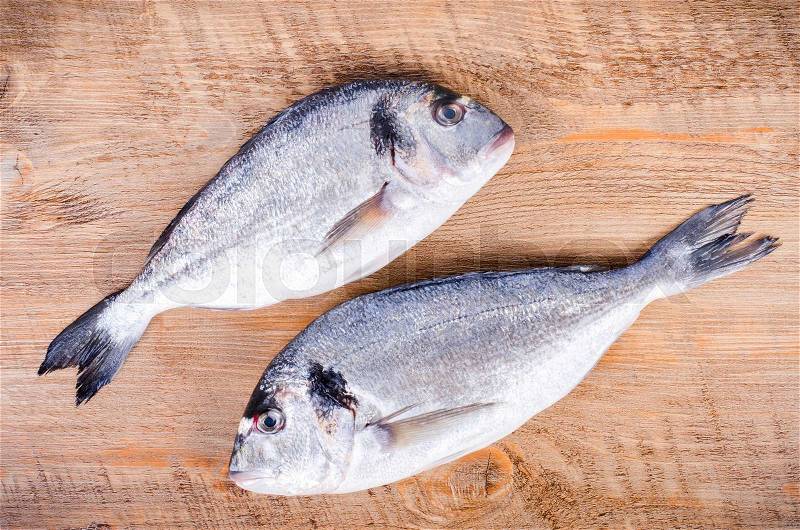 Fresh raw gilthead fishes on wooden background. Healthy food concept. Food frame, stock photo