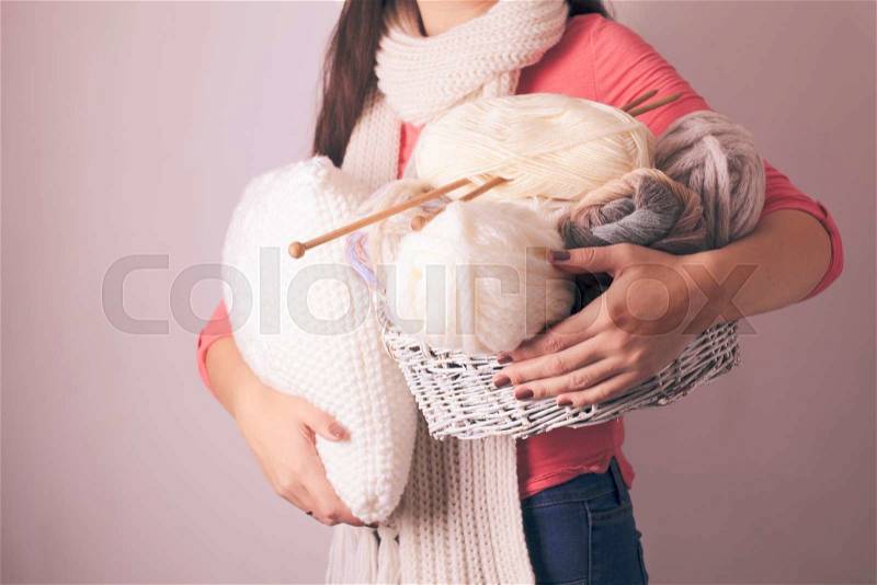 Warmly dressed woman holding a white knitted pillow, stock photo