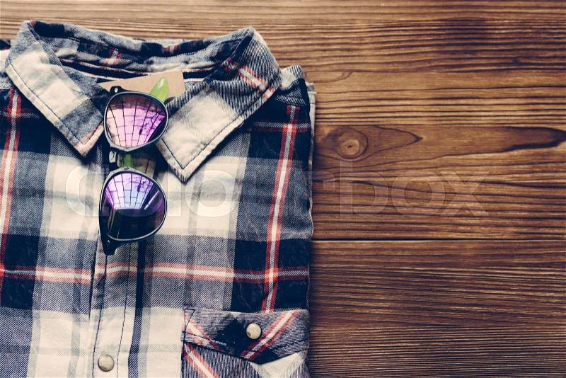 Men\'s plaid shirt and colored glasses on a wooden background. Top view, copy space, stock photo