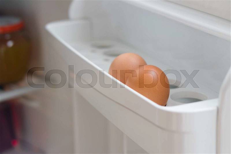 Two chicken eggs on a shelf of the refrigerator door open closeup, stock photo