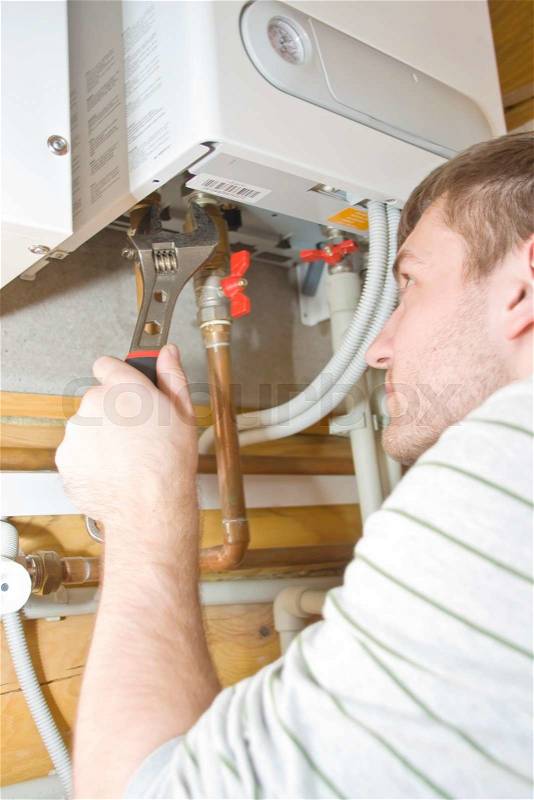 Plumber at work. Servicing gas boiler, stock photo