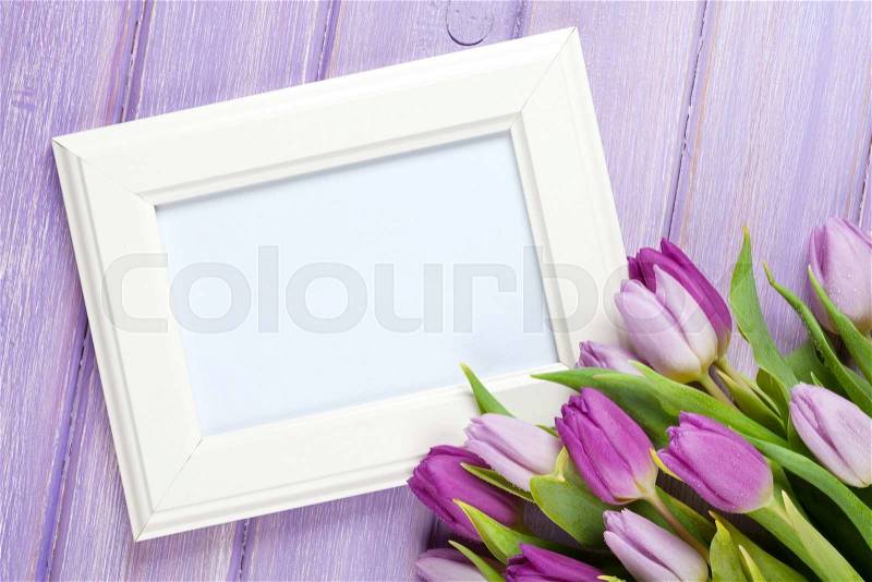 Purple tulip bouquet and blank photo frame. Top view over wooden table, stock photo