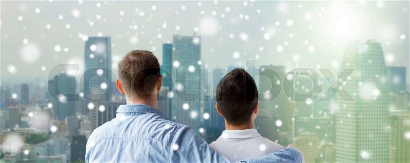People, homosexuality, same-sex marriage, gay and love concept - close up of happy male gay couple or friends hugging from back over city background and snow effect, stock photo